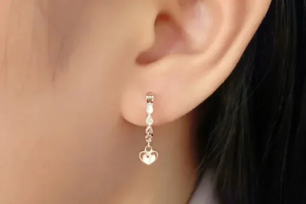 Anting emas menjuntai ke bawah dengan bentuk hati