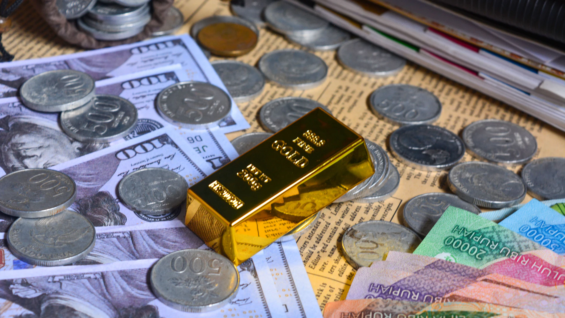 Emas batangan dikelilingi uang rupiah dan dolar AS